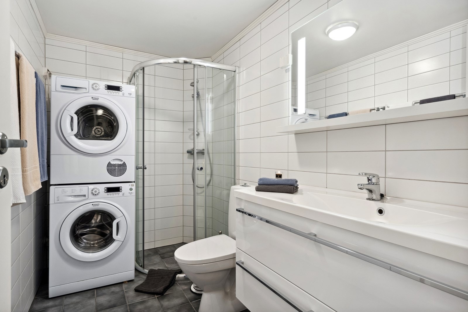 Badet er innredet med baderomsinnredning med servant, gulvmontert toalett og dusjhjørne, samt opplegg for vaskemaskin/tørketrommel. Flislagte vegger og gulv med varmekabler. Galleribilde