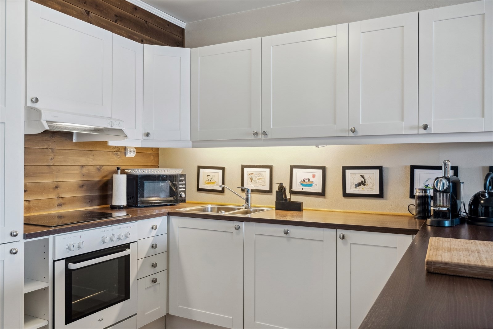 Benkeplate i laminat med nedfelt oppvaskkum, samt integrerte hvitevarer som komfyr og platetopp, oppvaskmaskin og kjøl-/fryseskap. Galleribilde