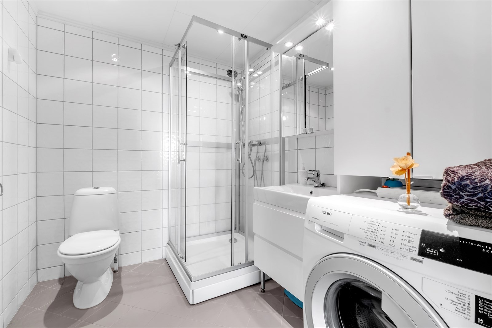 Overflater på badet er utført med flislagte vegger og himlingsplater med innfelte downlights. Flislagt gulv med elektriske varmekabler. Galleribilde