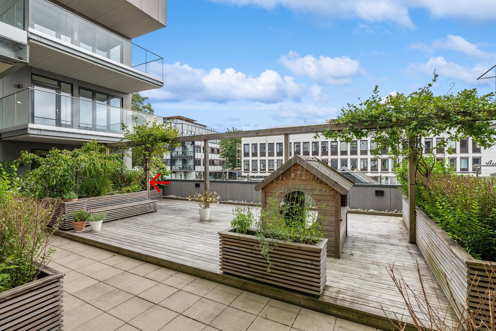 Sameiet har et meget hyggelig fellesområde, hvor denne leiligheten disponerer sin egen terrasse/uteområde. Rød pil. Det er i tillegg heis til takterrasse Galleribilde