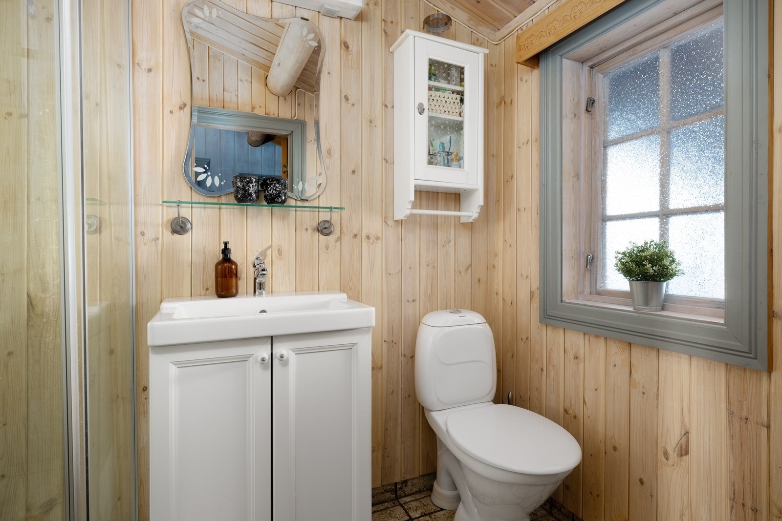 Badet er innredet med servant på innredning, toalett og dusjkabinett. Galleribilde