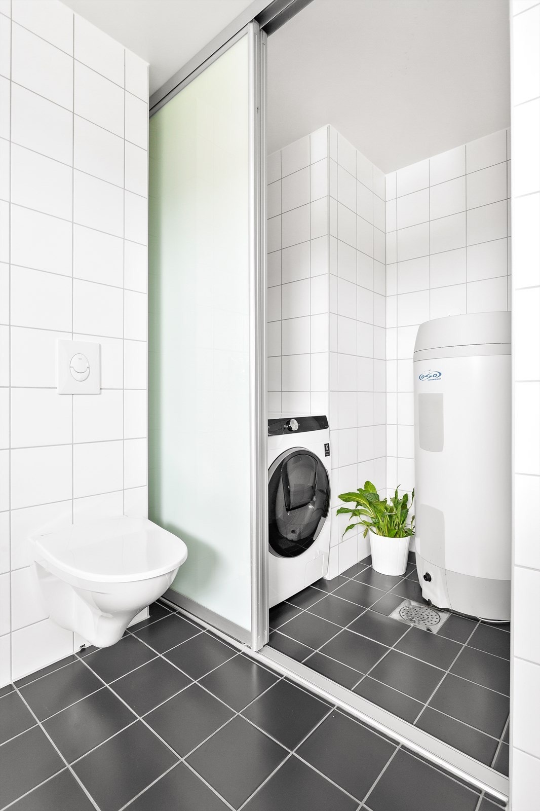 I vaskerommet er det flislagte overflater, sluk i gulvet, varmtvannsbereder og opplegg for vaskemaskin. Galleribilde