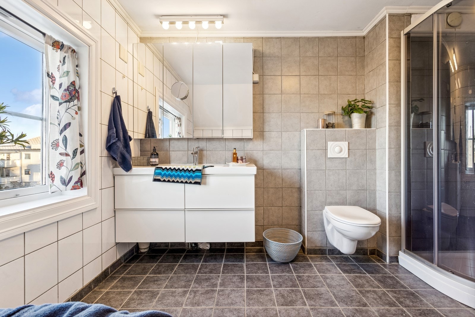 Baderommet har både badekar og dusjkabinett samt praktisk skuffeinnredning med nedfelt servant og speilskap over. Galleribilde