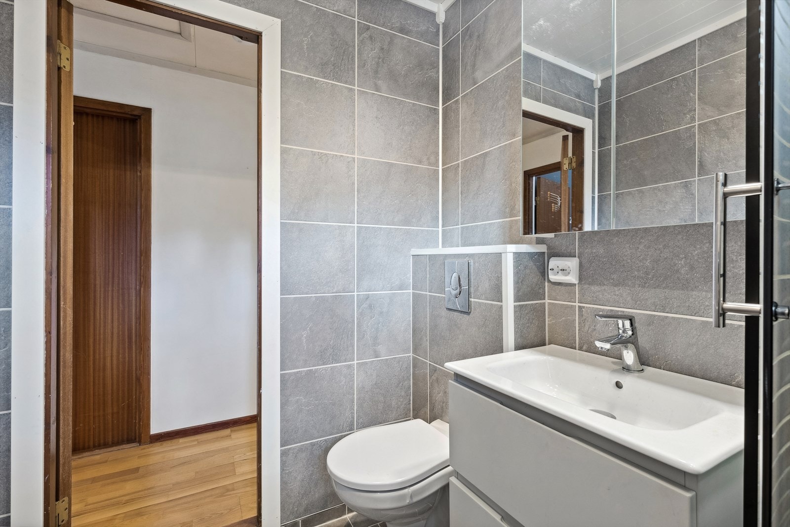 Badet inneholder baderomsinnredning, overskap med speildører, vegghengt toalett og dusjkabinett. Galleribilde