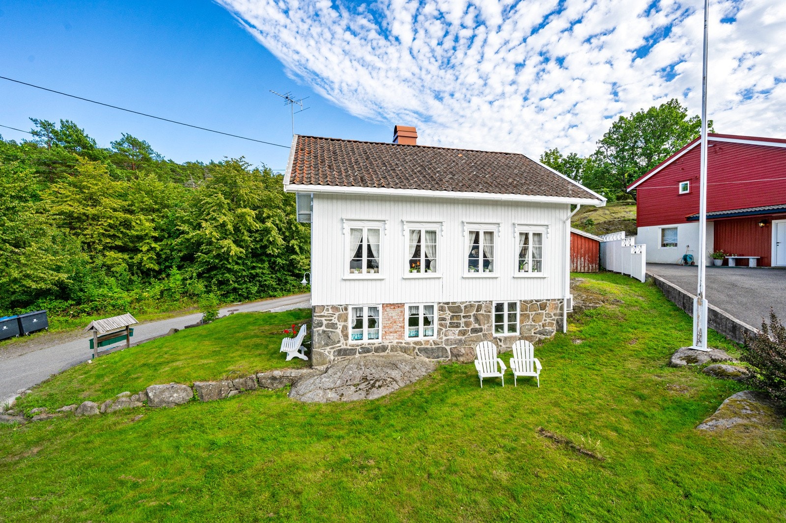 Koselig tomt som er enkelt med pent opparbeidet med plen, skrapet fjell, prydbusker, og flaggstang. Galleribilde