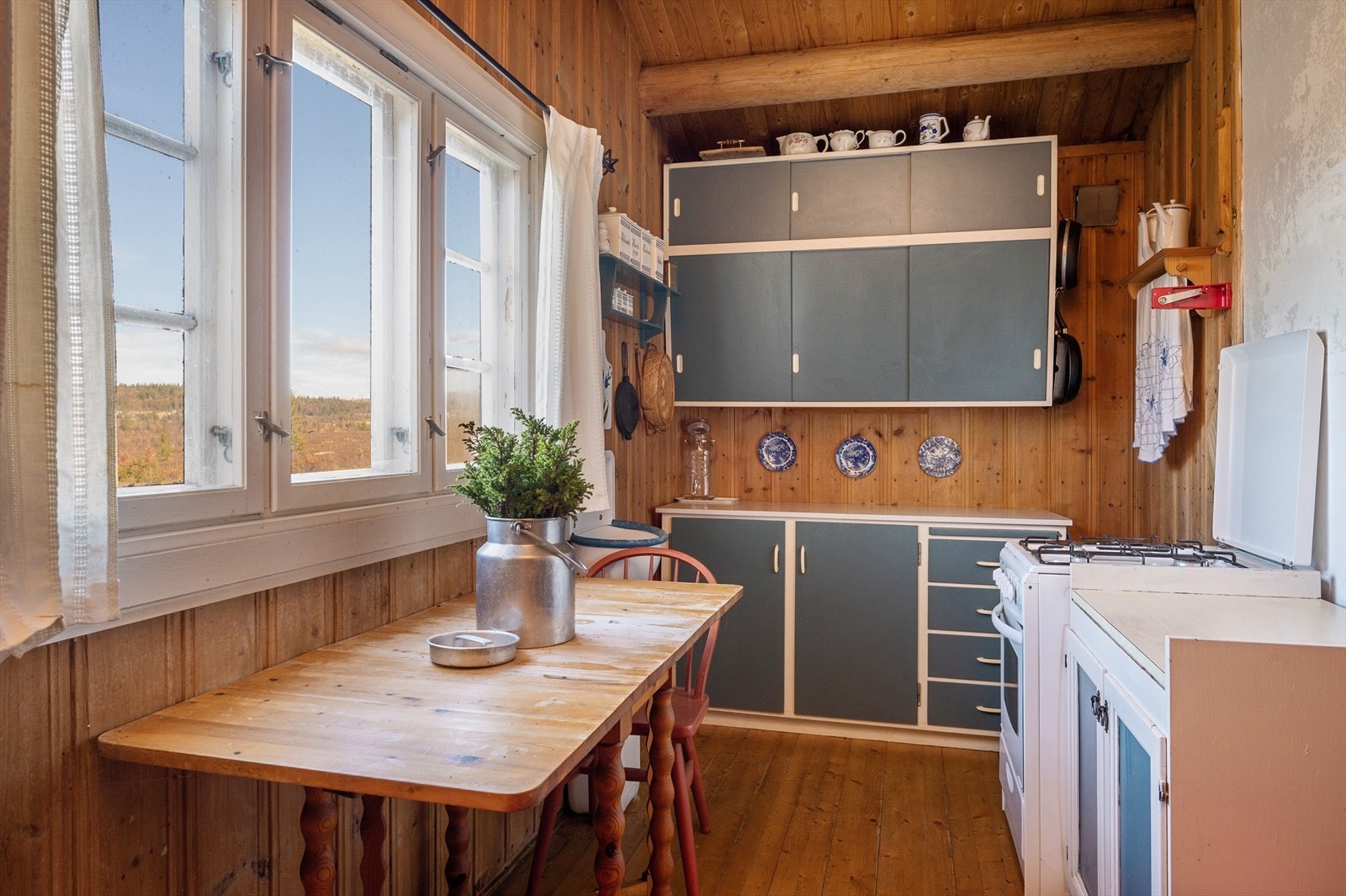 Kjøkkenet har eldre sjarmerende innredning med skrå overskap og skyvefronter Galleribilde