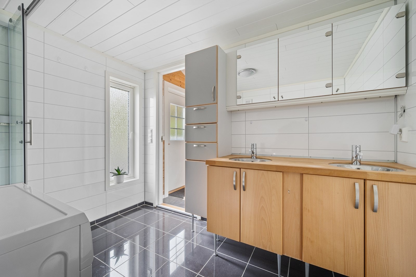Badet har gulvvarme, flislagt gulv, toalett, dusjkabinett og opplegg for vaskemaskin. Galleribilde