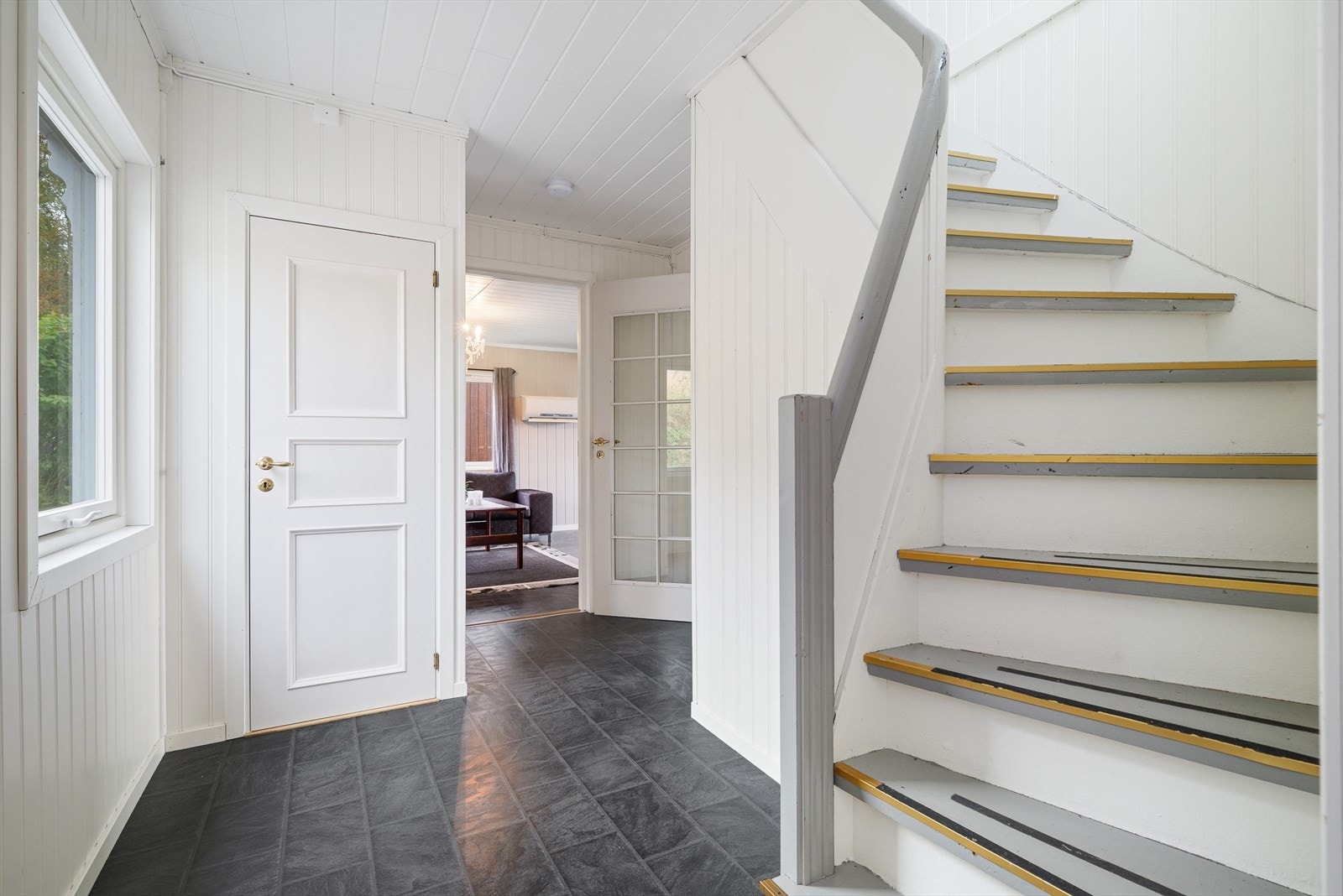 En tett trapp svinger seg opp til andre etasje. Det er også trapp ned til kjelleren herfra, via et lukket trapperom. Galleribilde