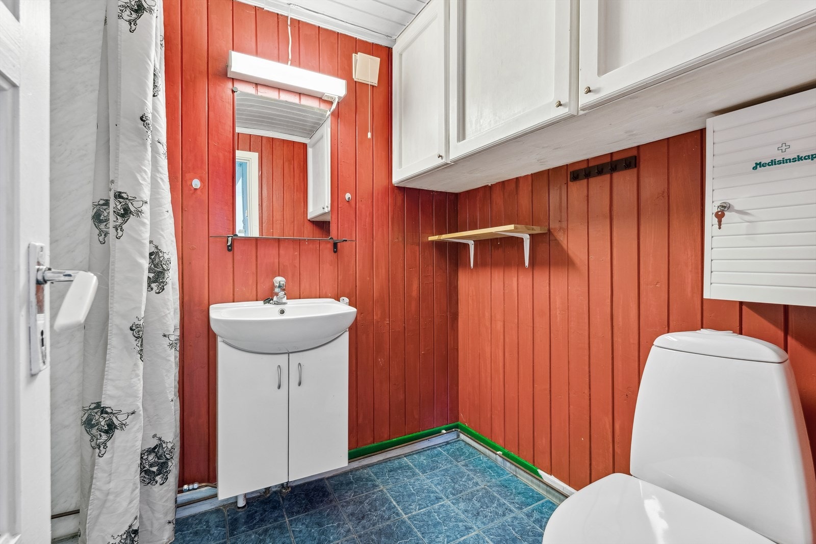 Bad med flis på gulv. Veggene er kledd med panel og baderomsplater i dusj. Galleribilde