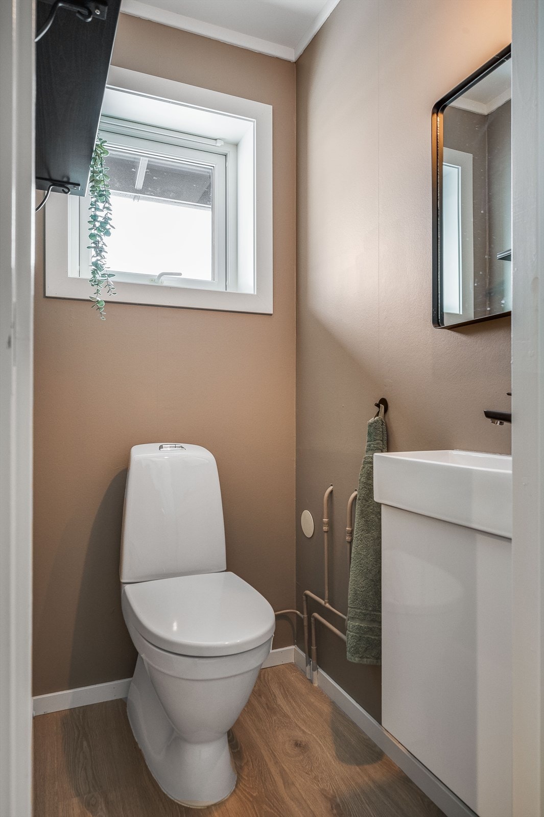 Toalettrom som ble pusset opp i 2023 med høytrykkslaminat og malte plater på vegger. Servant på underskap og toalett. Galleribilde