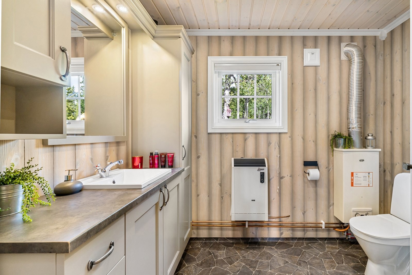 Badet er innredet med baderomsinnredning, dusjkabinett og toalett. Galleribilde
