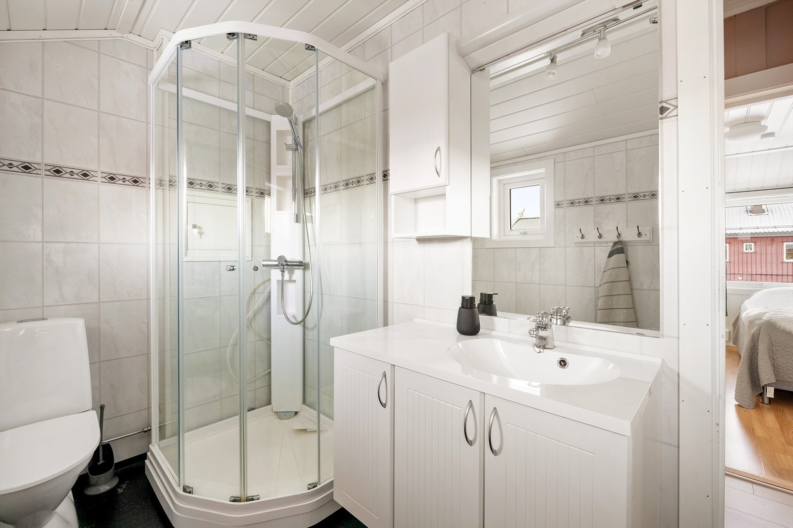 Badet inneholder servantinnredning med speil, dusjkabinett og frittstående toalett. Galleribilde