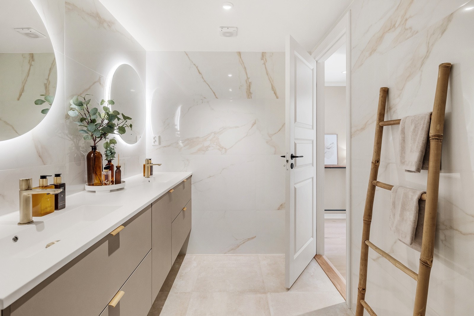 Innredningen har to heldekkende servanter over baderomsinnredning med skuffer, vegghengte speil med integrert belysning, dusjhjørne med innfellbare dører og regnfallsdusj og veggmontert wc. Galleribilde