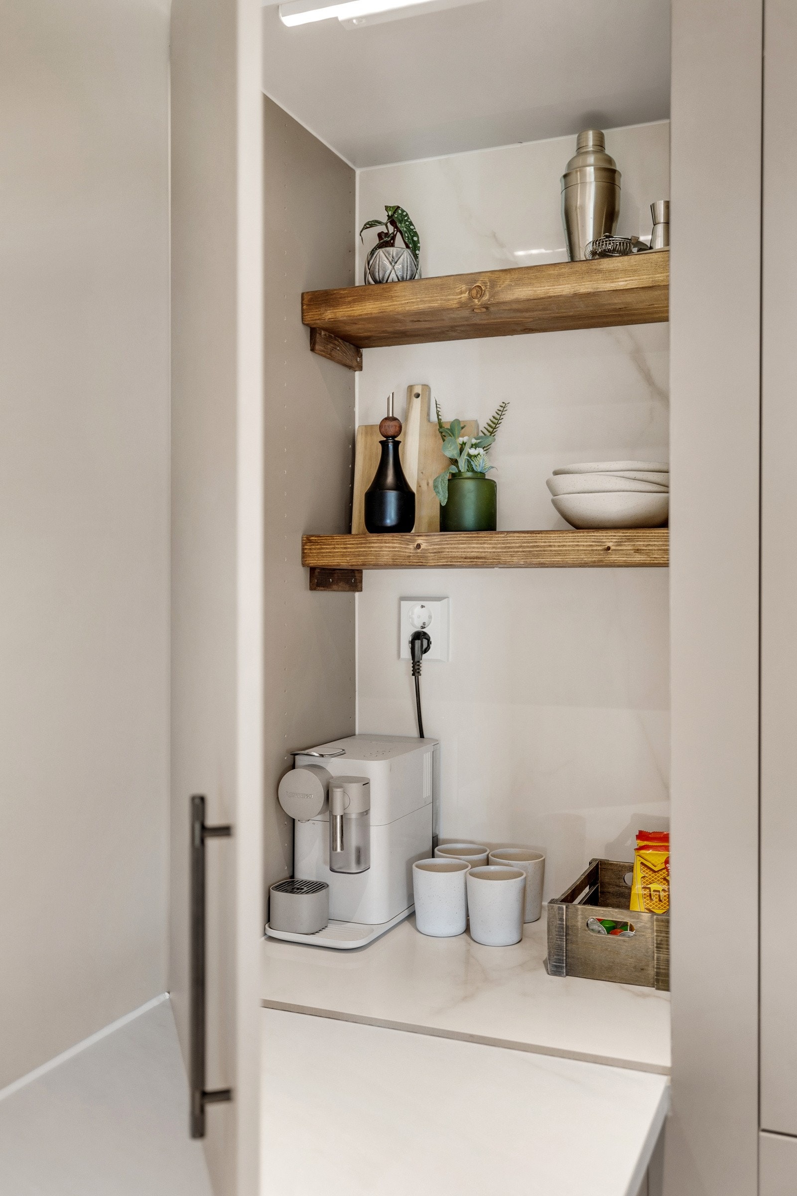 Leiligheten har smakfulle detaljer som i kjøkkenskapene med hyller i heltre og stikkontakt til kaffemaskinen. Galleribilde