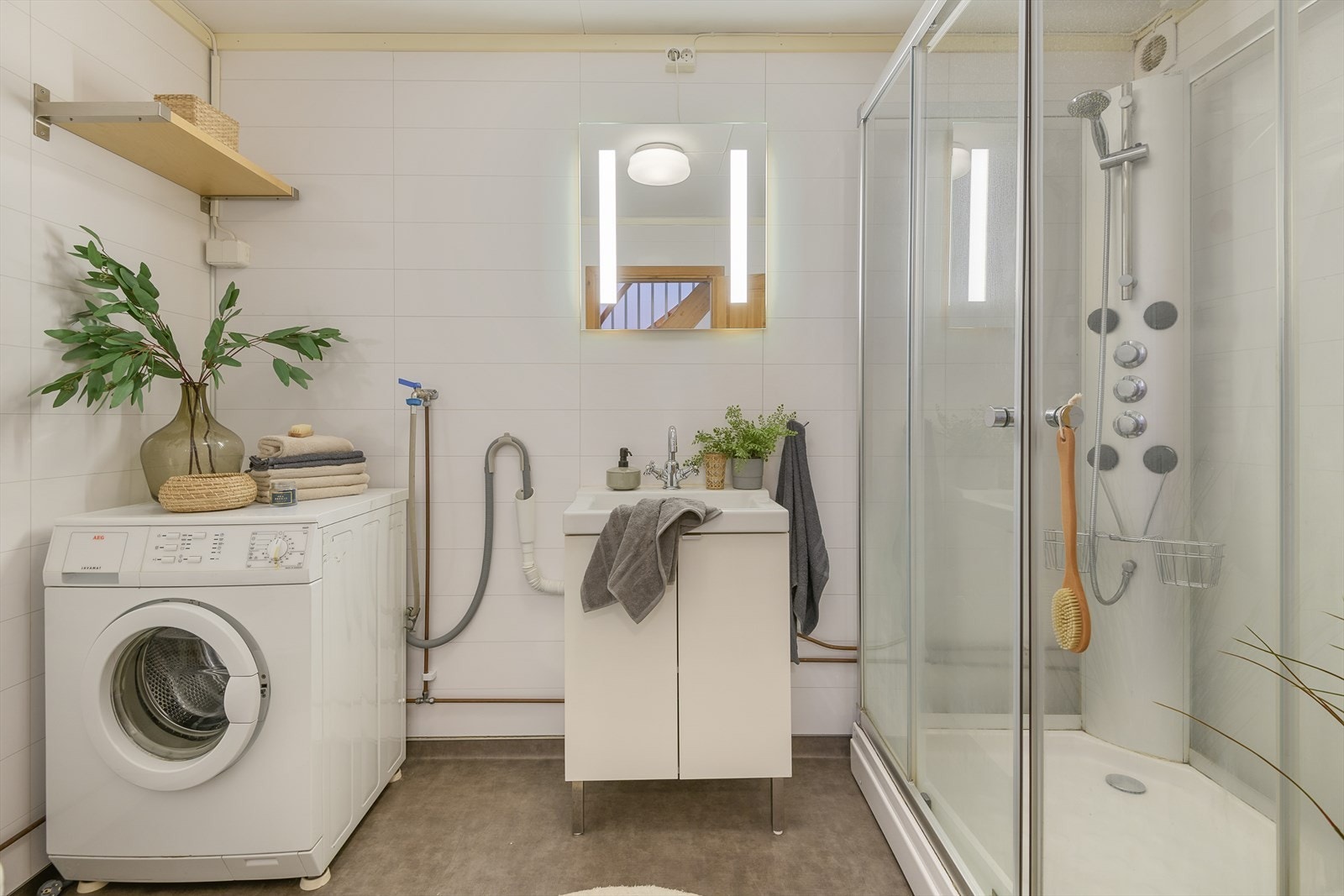 Videre er det dusjkabinett, gulvmontert toalett og opplegg for vaskemaskin på badet Galleribilde