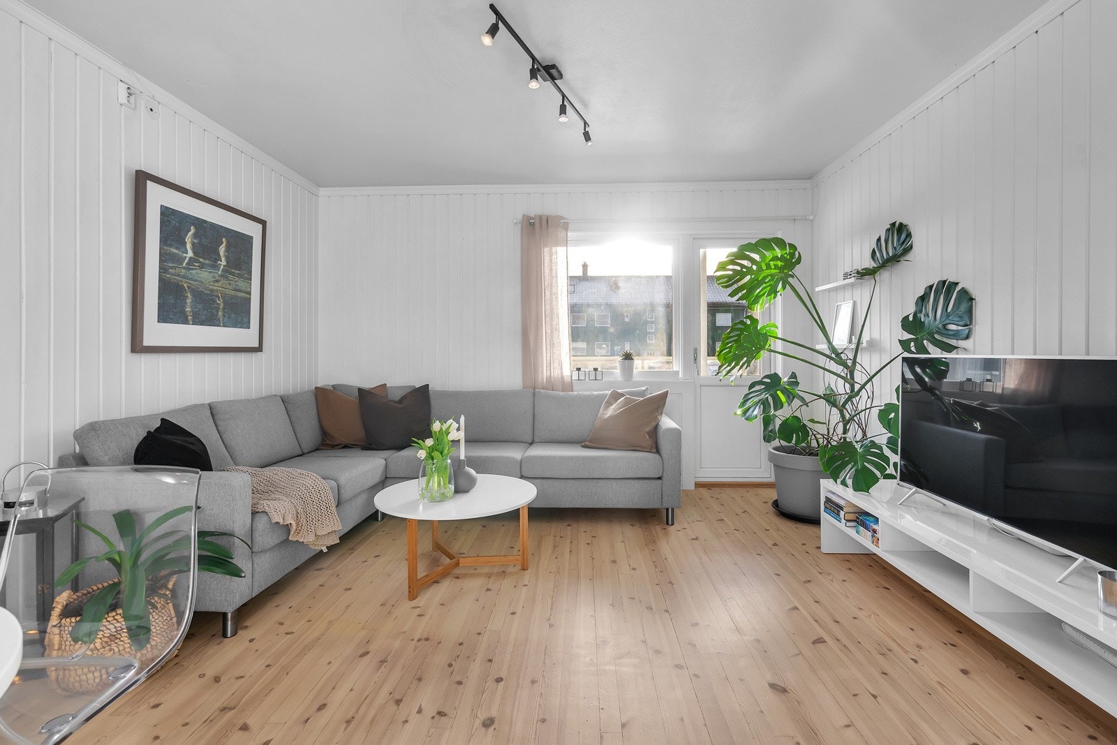 Romslig stue med mye lysinnslipp fra store vindusflater Galleribilde