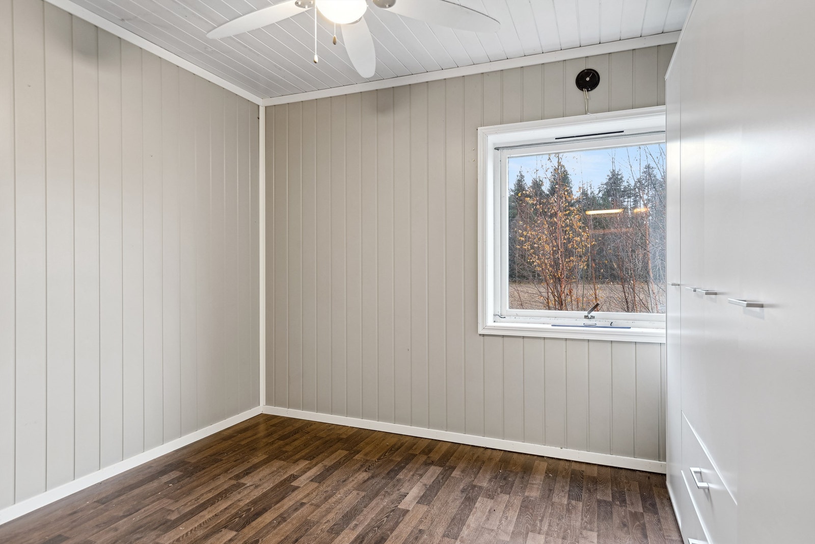 Det er tre soverom i boligen. Ett soverom med gråmalt panelplater på veggene og mørk laminat på gulvet. Rommet er etablert med garderobeskap med skapdører og skuffer. Galleribilde
