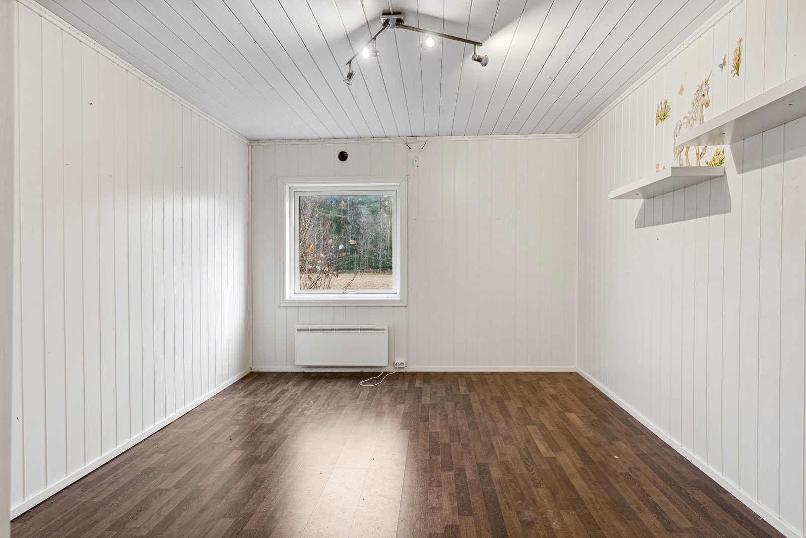 Det andre soverommet har hvitmalt panelplater på veggene og mørk laminat på gulvet. Rommet er romslig, og med panelovn montert på veggen. Galleribilde