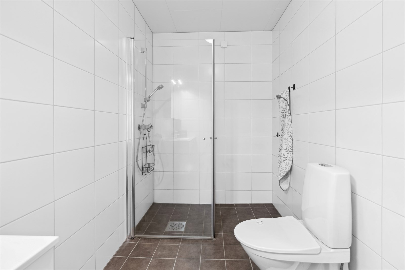 Badet er innredet med dusjhjørne, klosett og servantskap Galleribilde