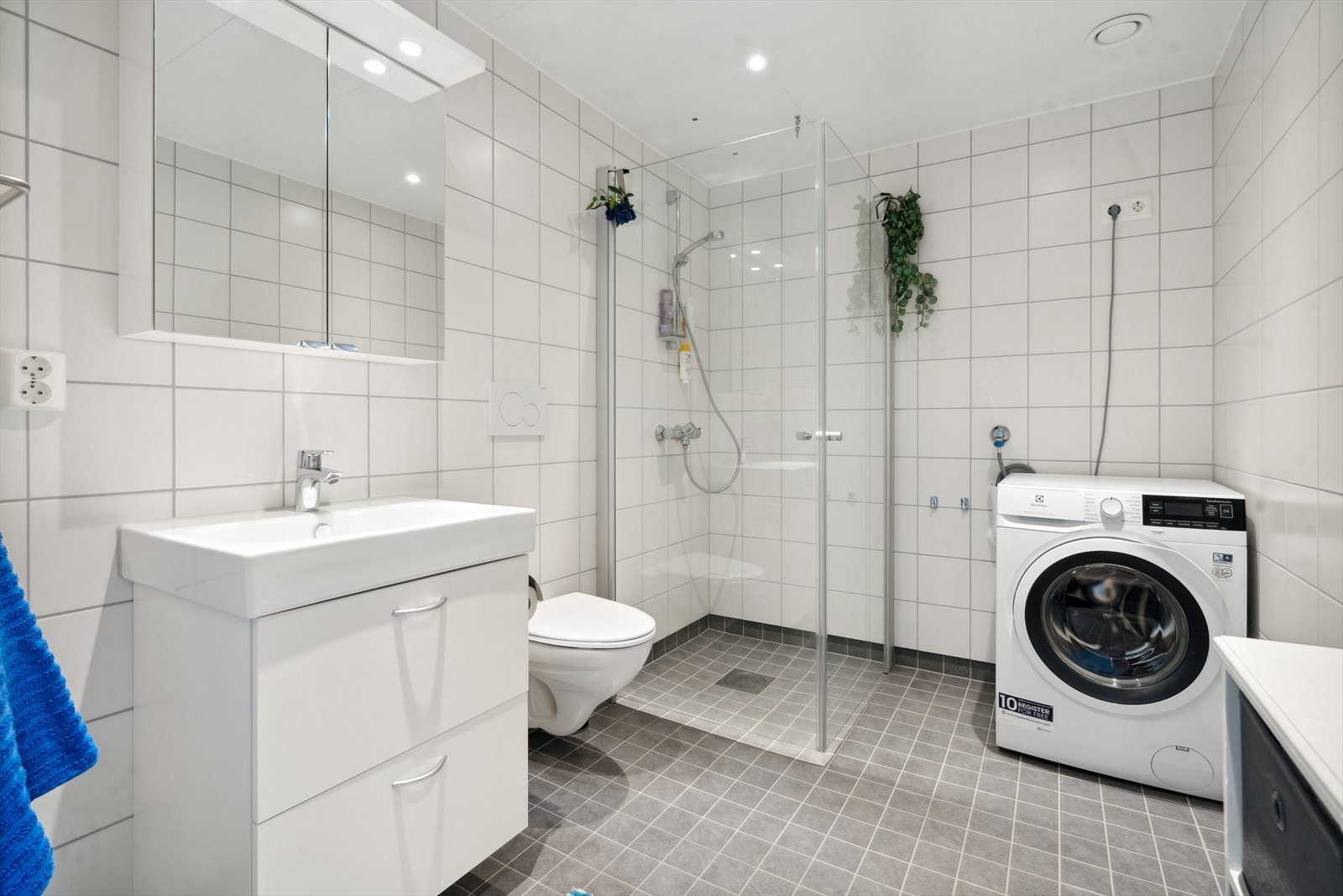 Baderomsinnredning, vegghengt toalett, dusjnisje med glassvegger, opplegg for vaskemaskin, Varme i gulv. Galleribilde