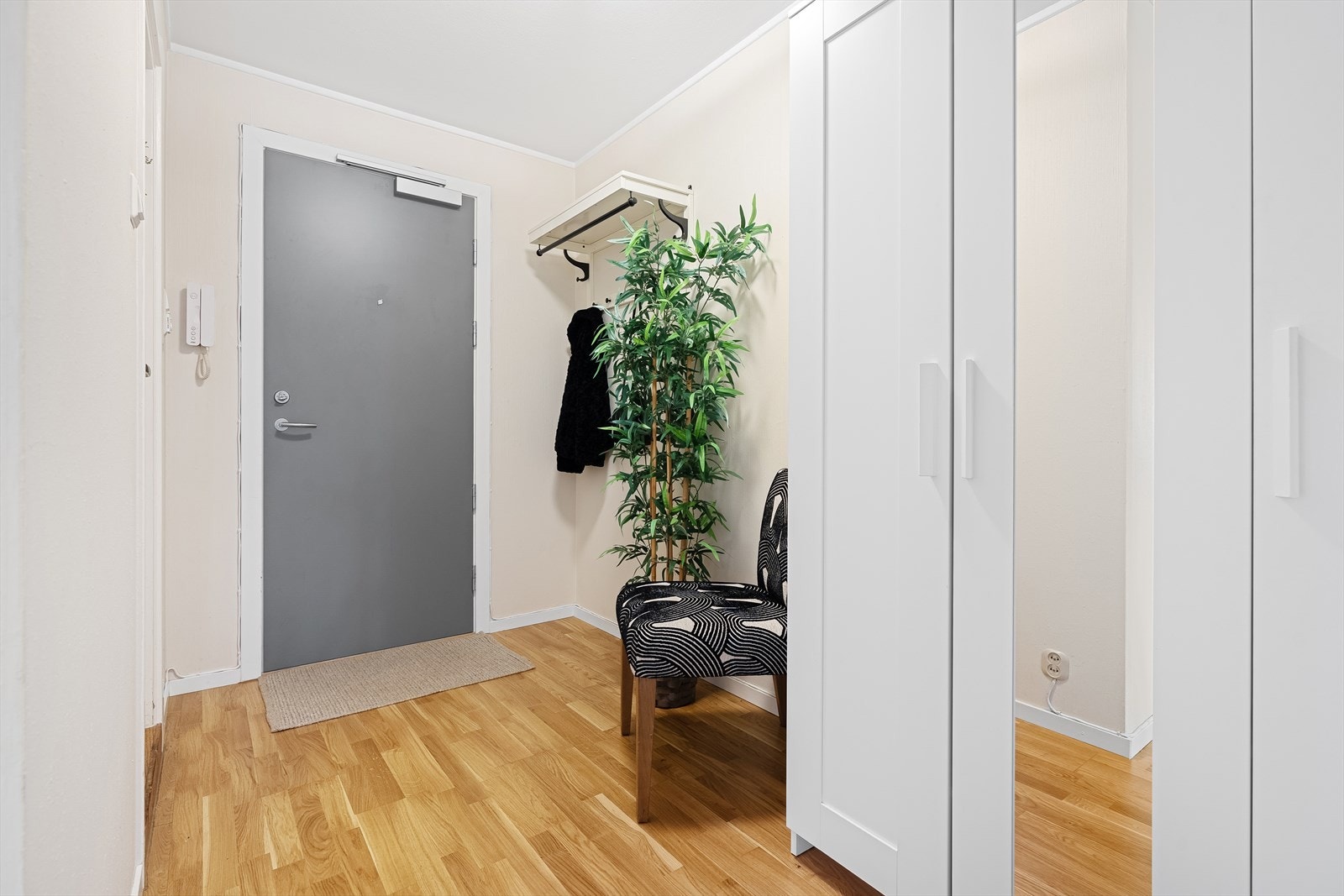 I entreen er det plass til å henge fra seg ytterjakka og sette fra seg skoene. Det er også satt opp et praktisk garderobeskap her, som også medfølger leiligheten. Porttelefon slipper enkelt inn gjester i bygget. Galleribilde