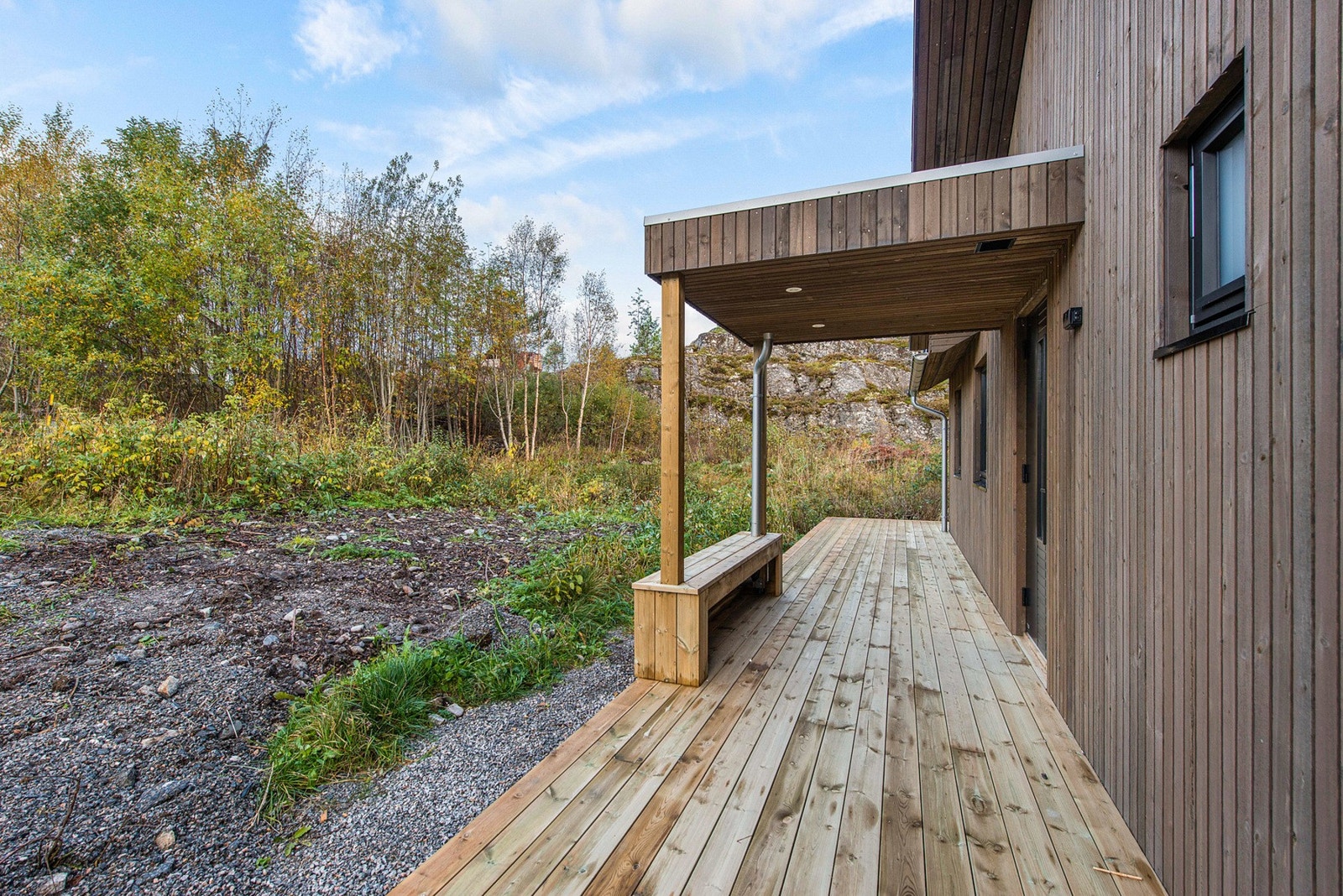 Overbygd inngangsparti med benk. Galleribilde