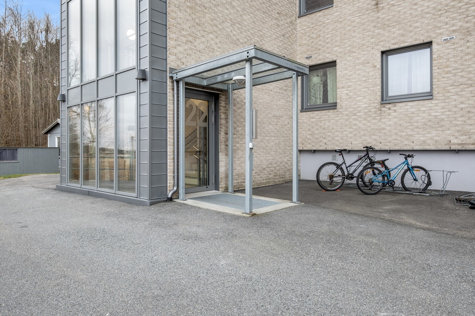 Overbygget inngangsparti og parkering for sykler. Galleribilde