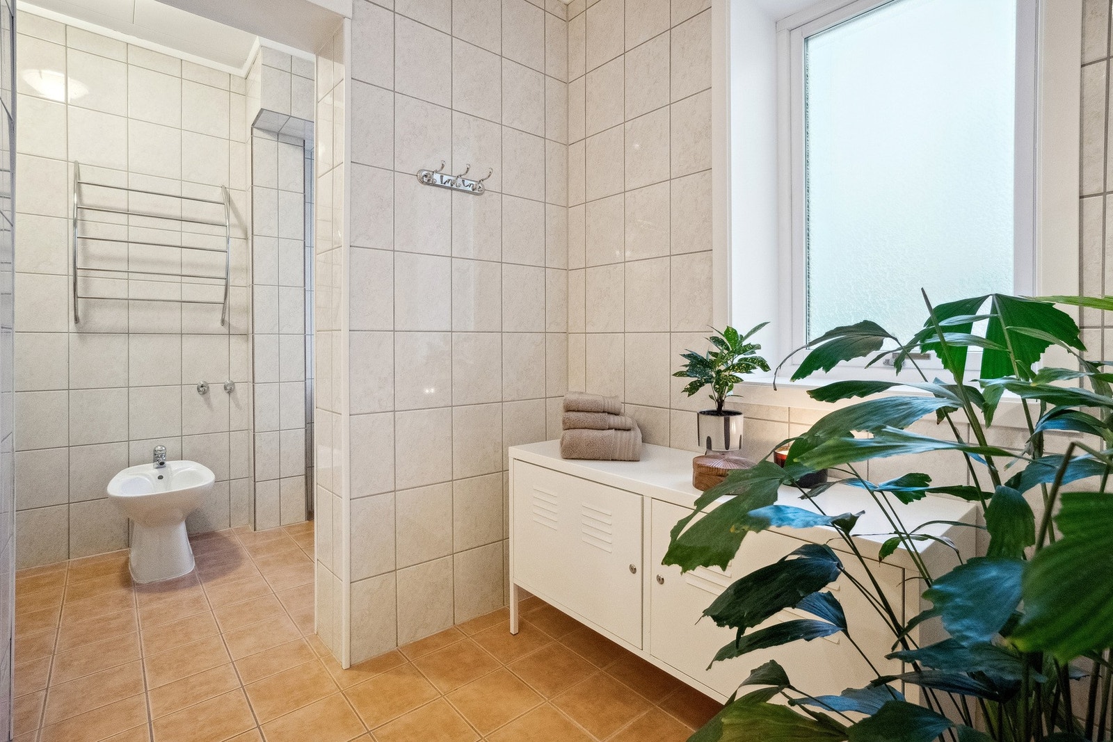 Badet har dusjkabinett, toalett, bidet, skyllekar på vegg og opplegg for vaskemaskin Galleribilde