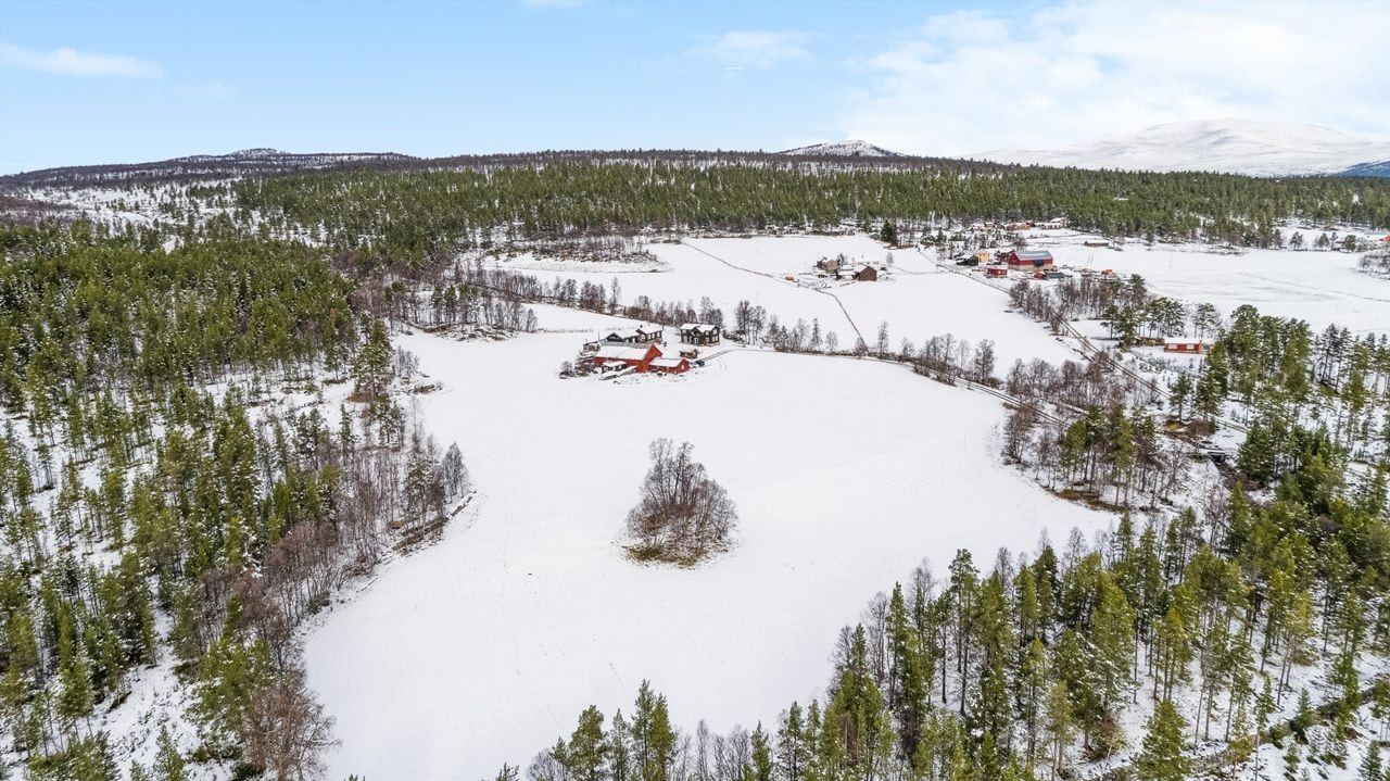 Dronebilde over eiendommen og grenda med vinterfjellet i bakgrunnen Galleribilde