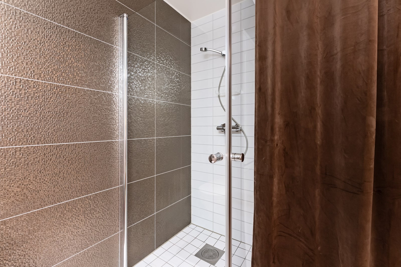 Dusjhjørne og mulighet for vaskemaskin og tørketrommel i søyle bak forheng. Galleribilde