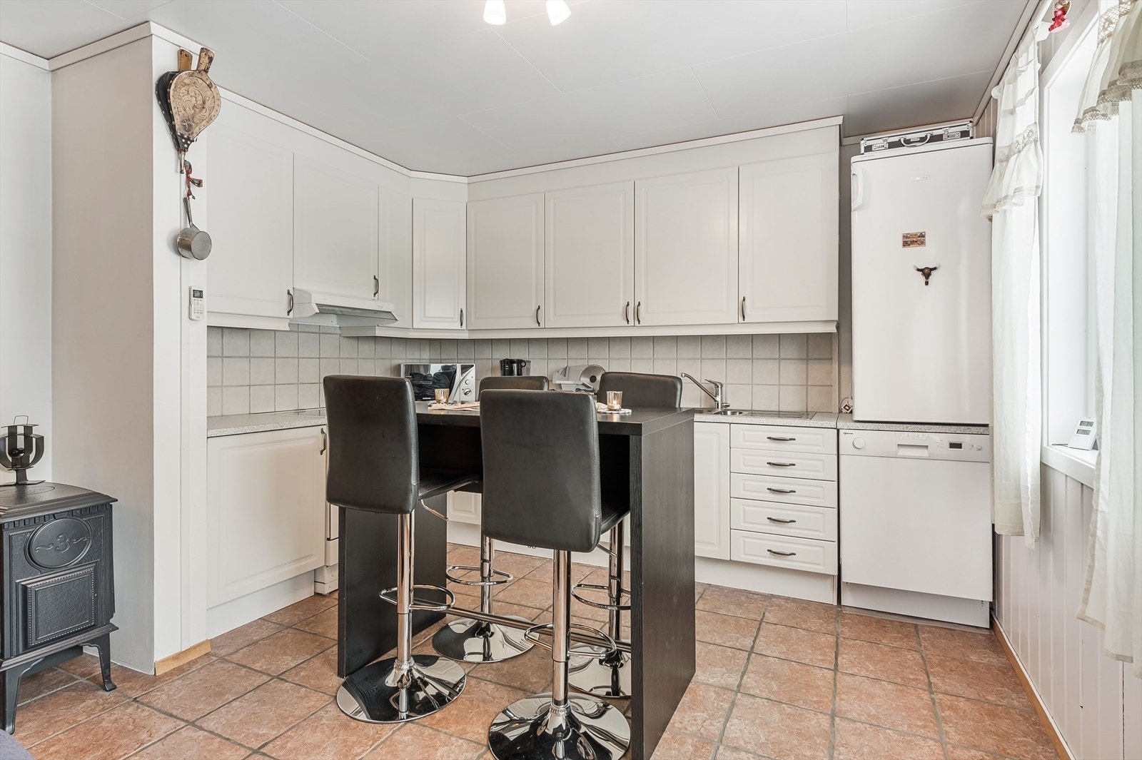 Lyst kjøkken med sitteplasser ved kjøkkenøy Galleribilde