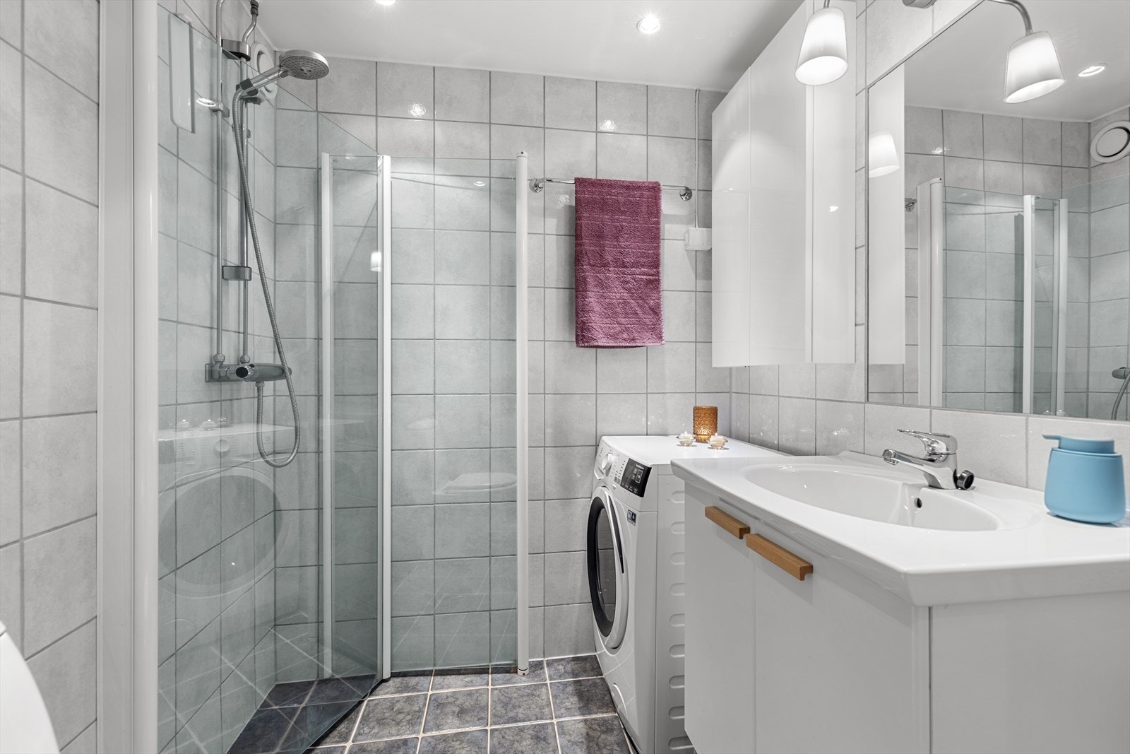 Badet har innredning med nedfelt servant, toalett, dusjvegger/hjørne og opplegg for vaskemaskin. Galleribilde