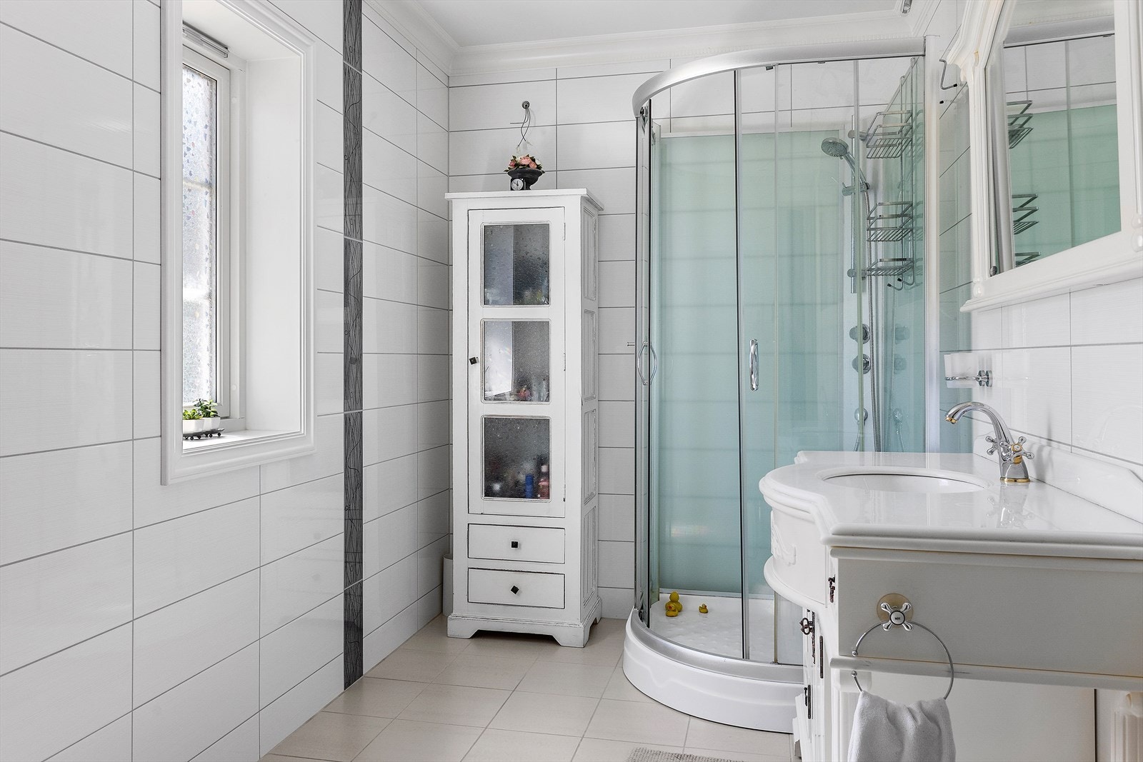 Badet er helfliset med servant i innredning og dusjkabinett og toalett. Galleribilde