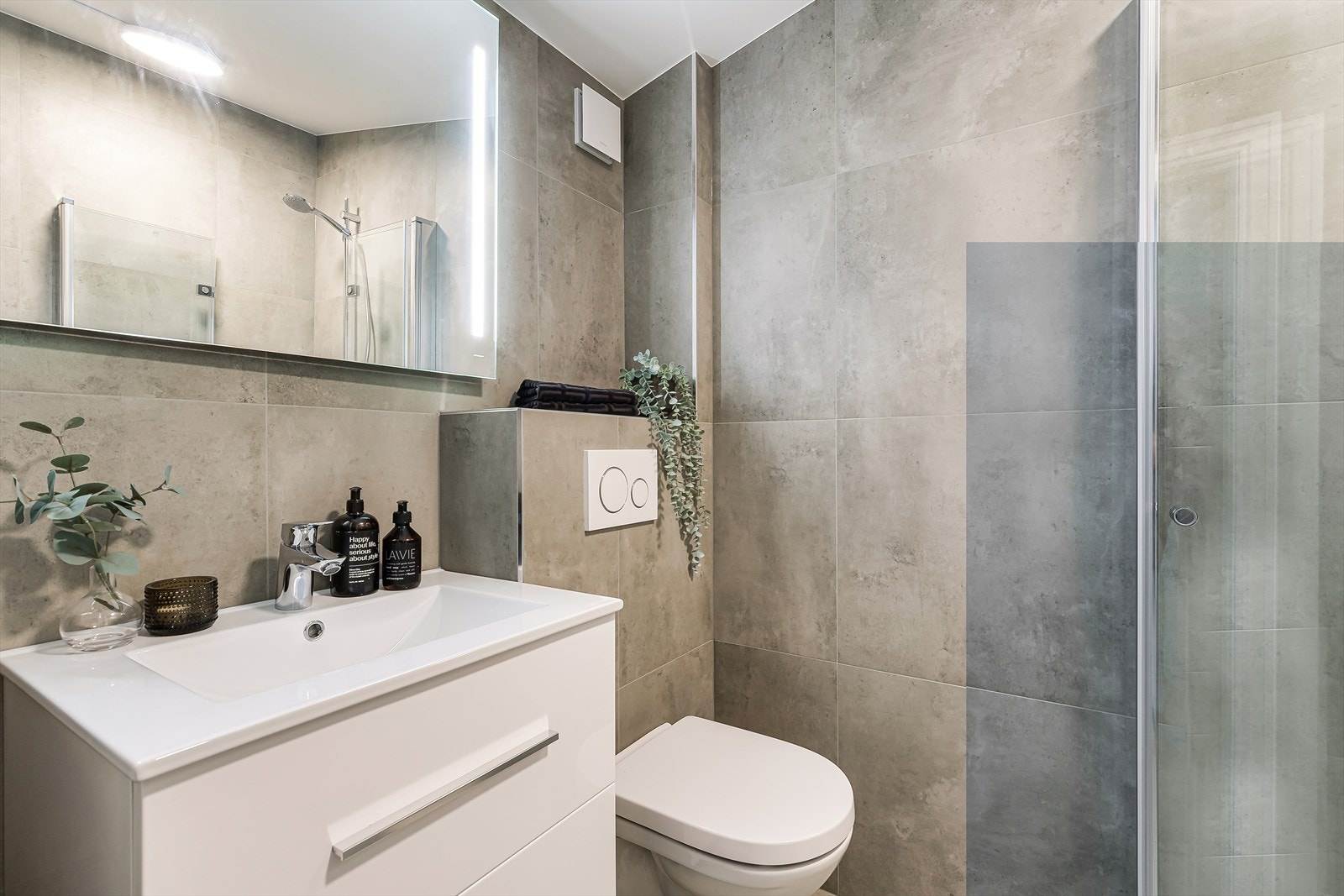 Innredningen består av servantskap med heldekkende servant, speil med lysarmatur og et romslig dusjhjørne med innfellbare dører. Galleribilde