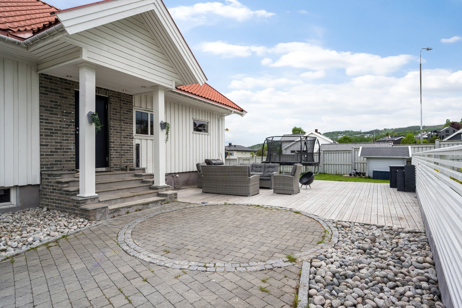Tomten er pent opparbeidet med plen, blomster og brosteinsbelagt gårdsplass. Galleribilde