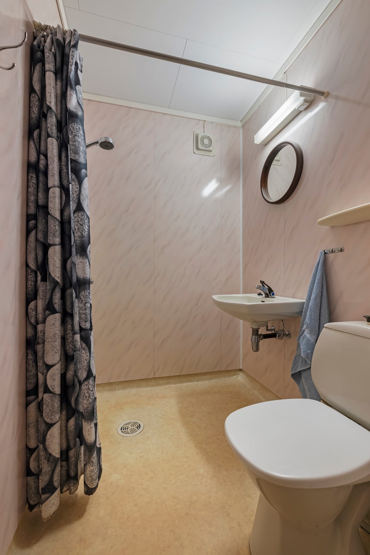 Bad i kjeller har vinylbelegg på gulv med varme, vegghengt servant, gulvstående toalett og dusj med forheng Galleribilde