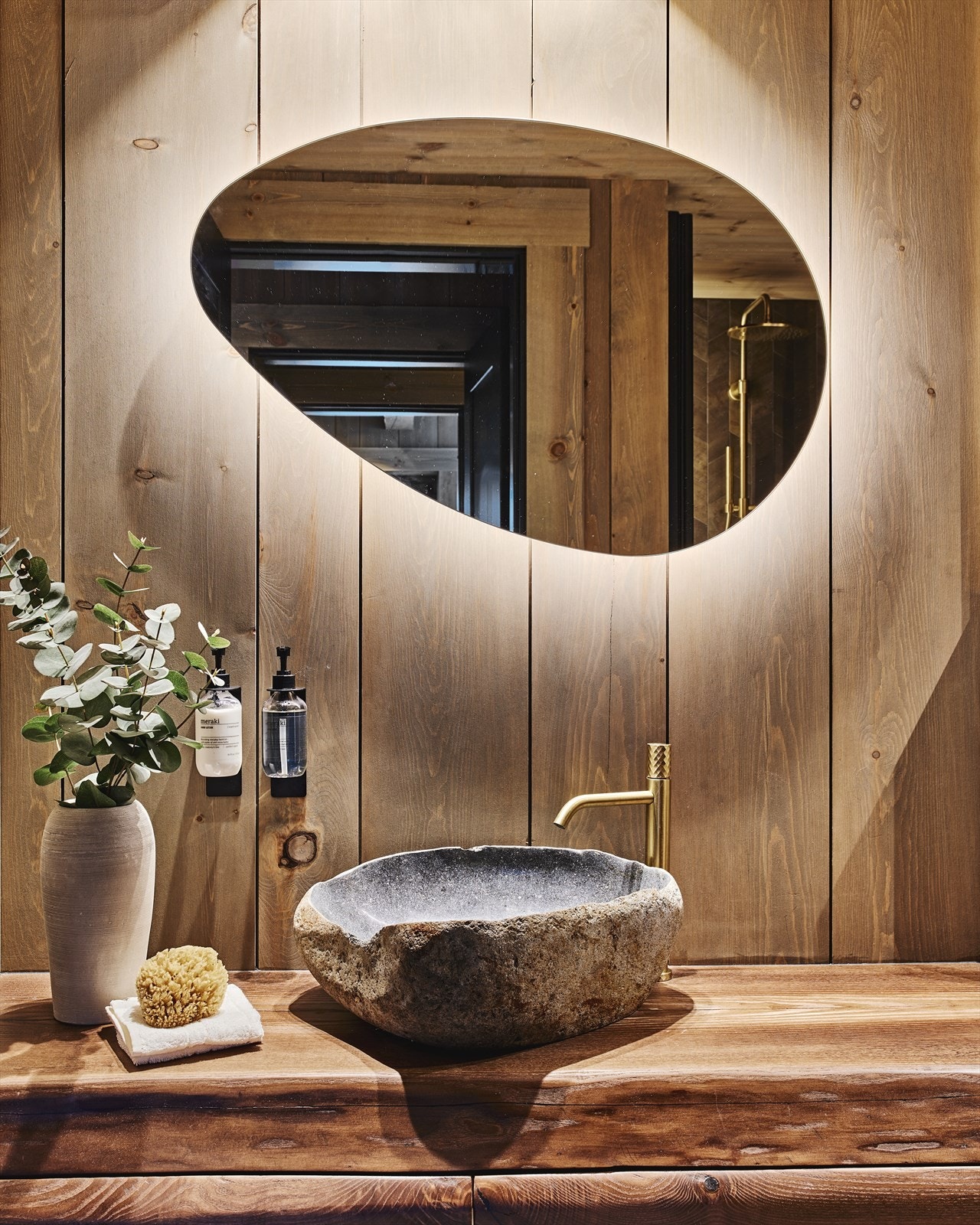 Servantskap i brunbeiset organisk forma treverk, steinvask fra Bali (levert av By Bjørkheim) og servantbatteri i børsta gull fra Spillo tech. Baderømsmøblene i alle bad er laget av norske og lokale tuntre i ask - hogd i Nordfjord. Galleribilde