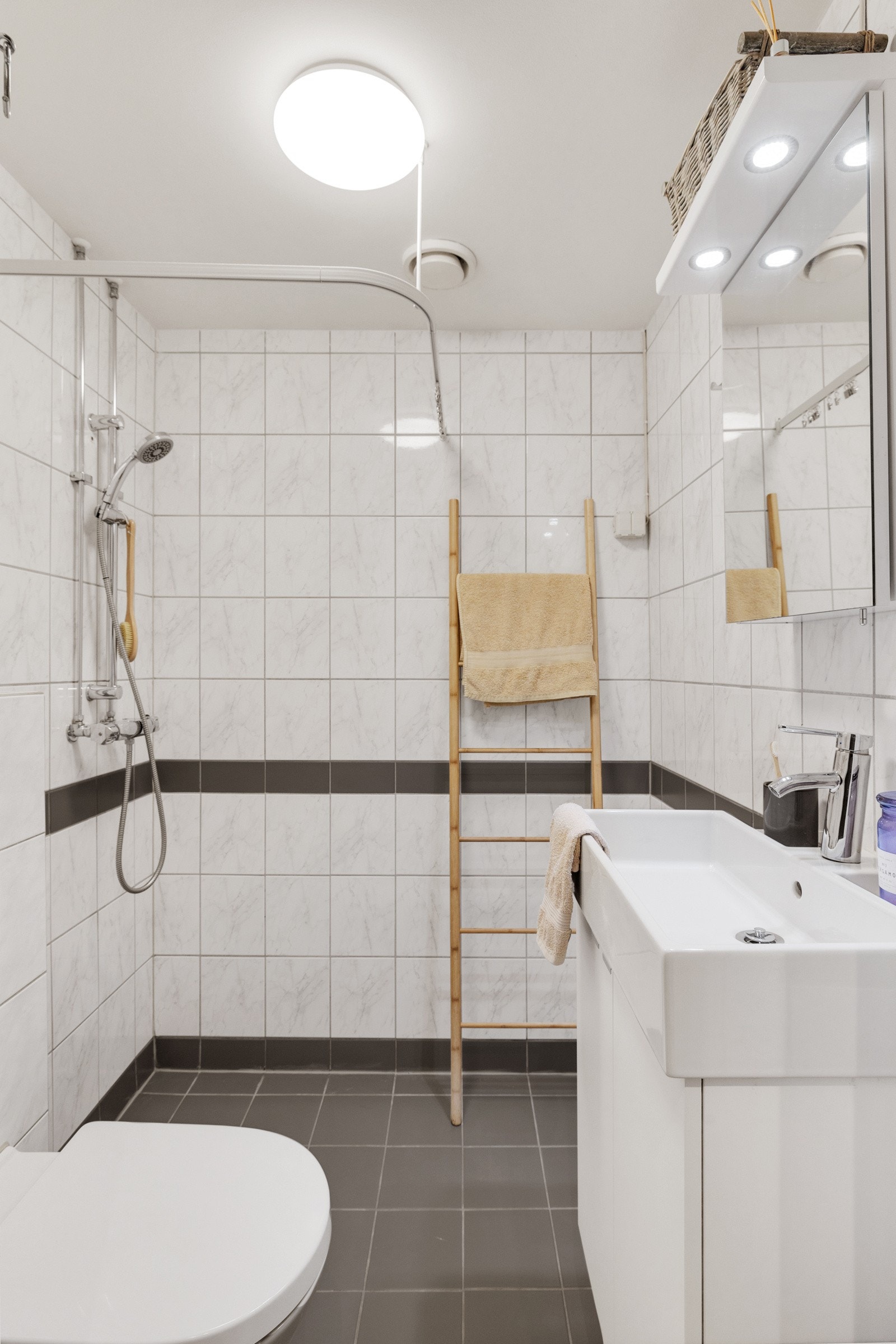 Badet inneholder vegghengt servantskap med heldekkende servant, speilskap med belysning, vegghengt wc og dusjhjørne. Galleribilde