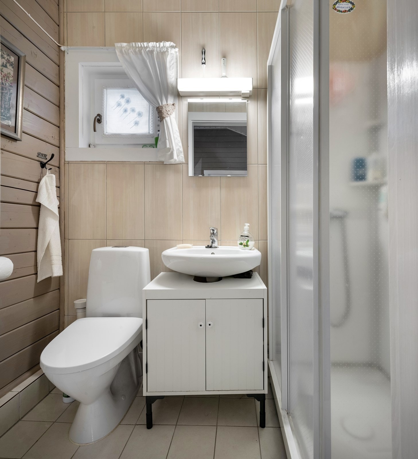 Bad i den minste hytta innredet med toalett, servant på innredning og dusjkabinett. Galleribilde