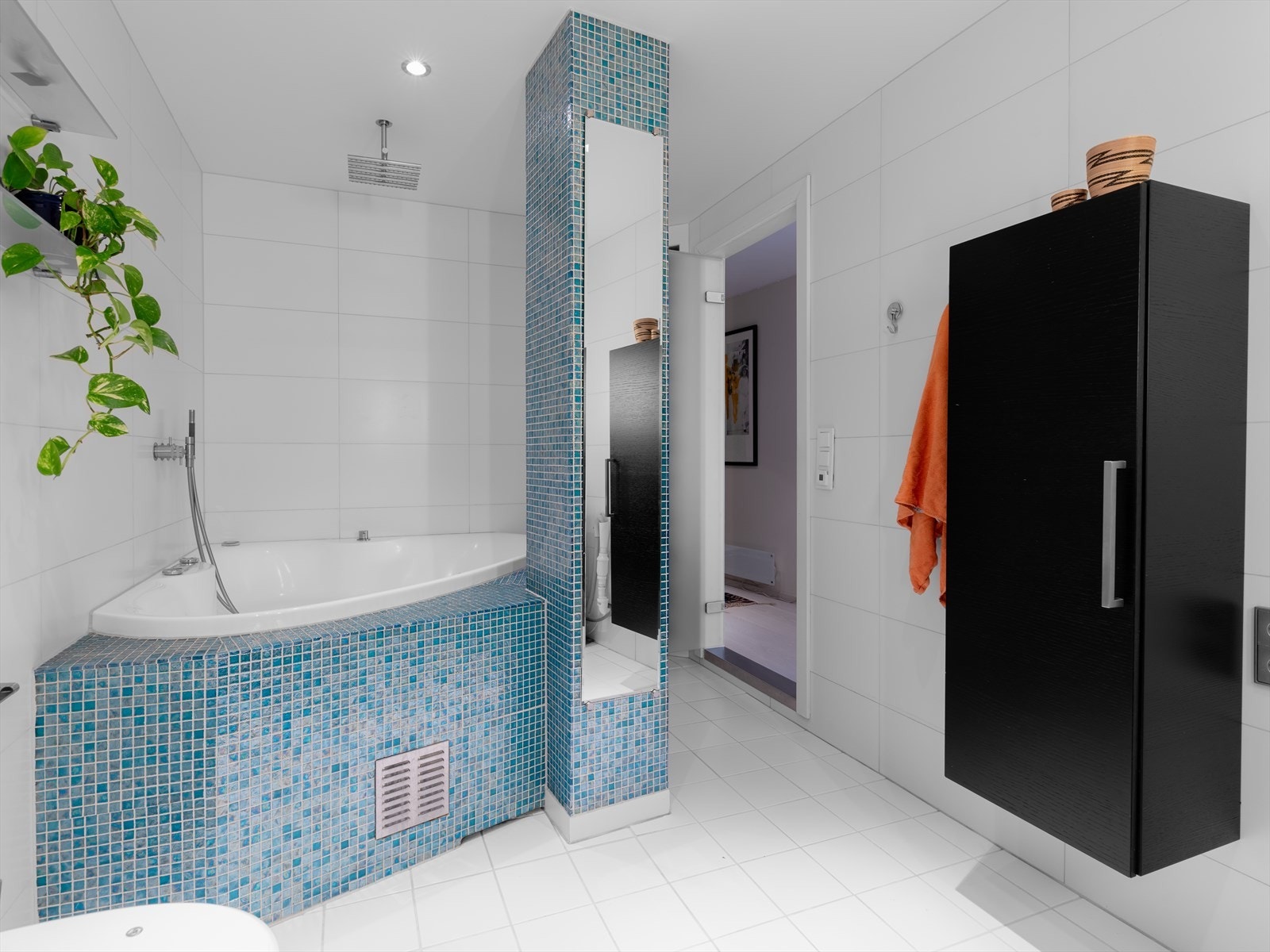 Det er mosaikkflis rundt boblebadet og innfliset hjørne-boblekar med takmontert regnfall dusjhode. Galleribilde