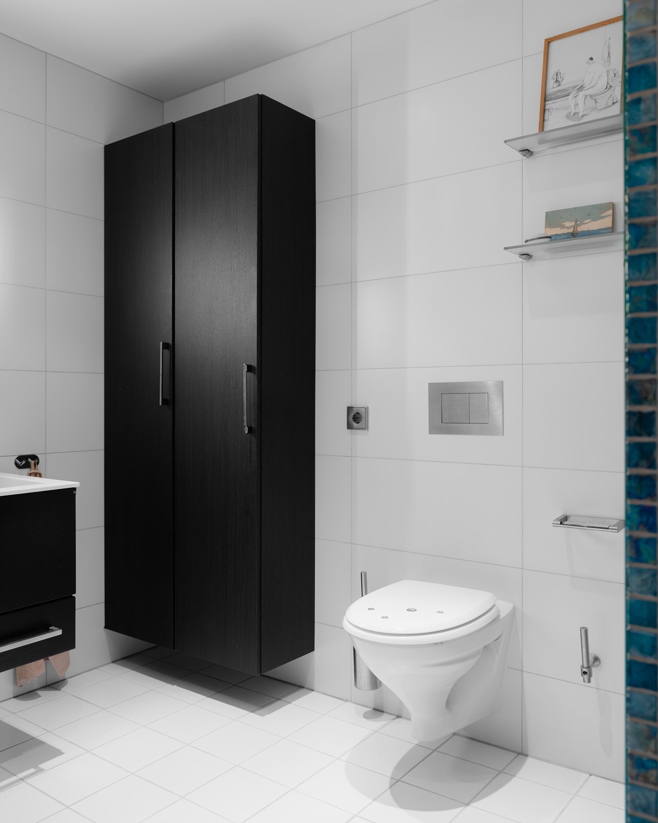 Badet er utstyrt med servantskap med skuffer, vegghengt oppbevaringsskap, veggmontert speil med integrert belysning og vegghengt klosett. Galleribilde