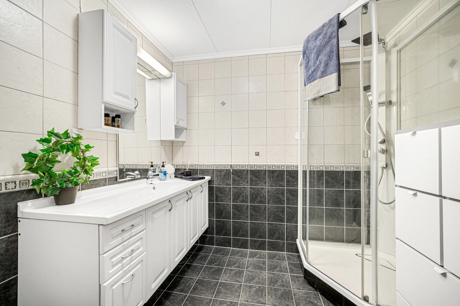 Flislagt bad med varmekabler i gulv. Romslig innredning og moderne dusjkabinett fra Porsgrund. Galleribilde