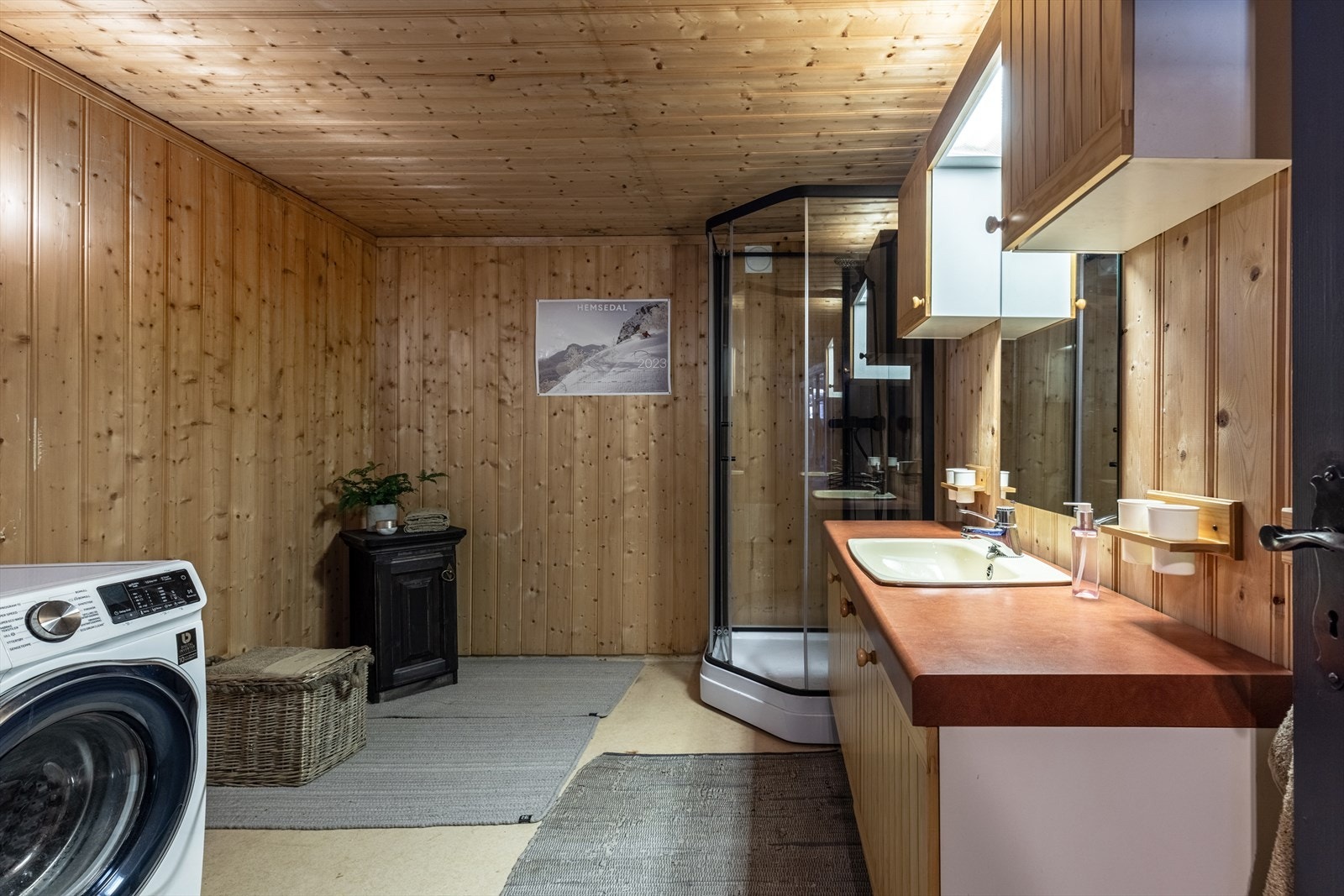 Romslig bad med innredning og nedfelt servant, dusjkabinett og opplegg for vaskemaskin. Galleribilde