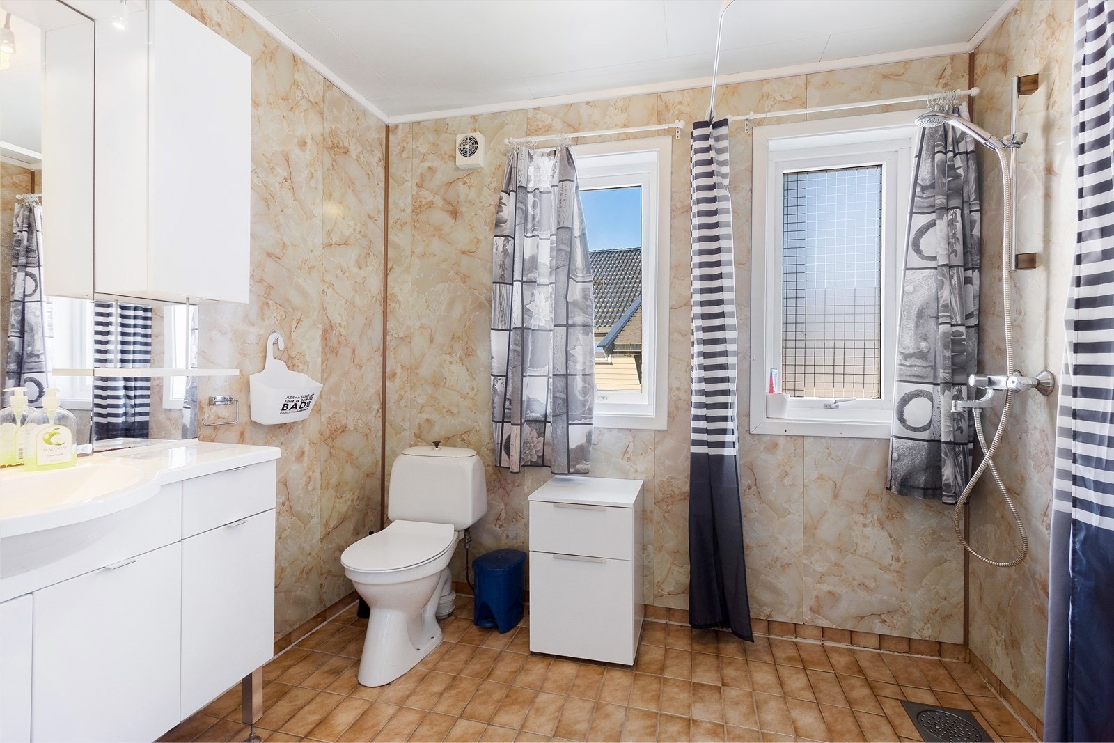 Badet er innredet med toalett, servant og dusj på vegg. Galleribilde