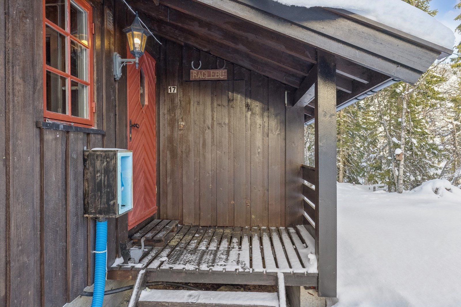 Inngangsparti. Bygningen er oppført på stripemurer av betong på byggegrunn av skogbunn. Bygningen har vannforsyning fra grunnboret brønn i brønnhus og utekran på yttervegg. Galleribilde