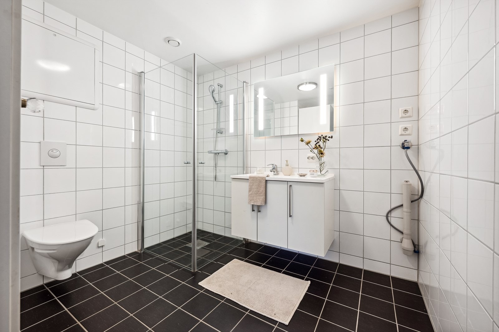 Badet er innredet med speil med belysning, heldekkende servant på hvitt servantmøblement, egghengt toalett, dusjhjørne med innsvingbare dusjdører, samt opplegg for vaskemaskin. Galleribilde