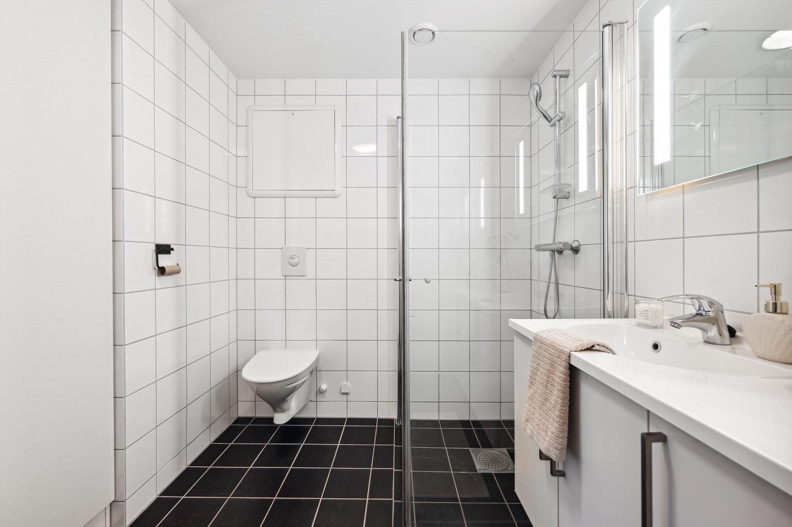 Badet fremstår med et tidløst, men samtidig moderne preg. Badet har grå gulvfliser, hvite veggfliser, gulvvarme og balansert ventilasjon. Galleribilde