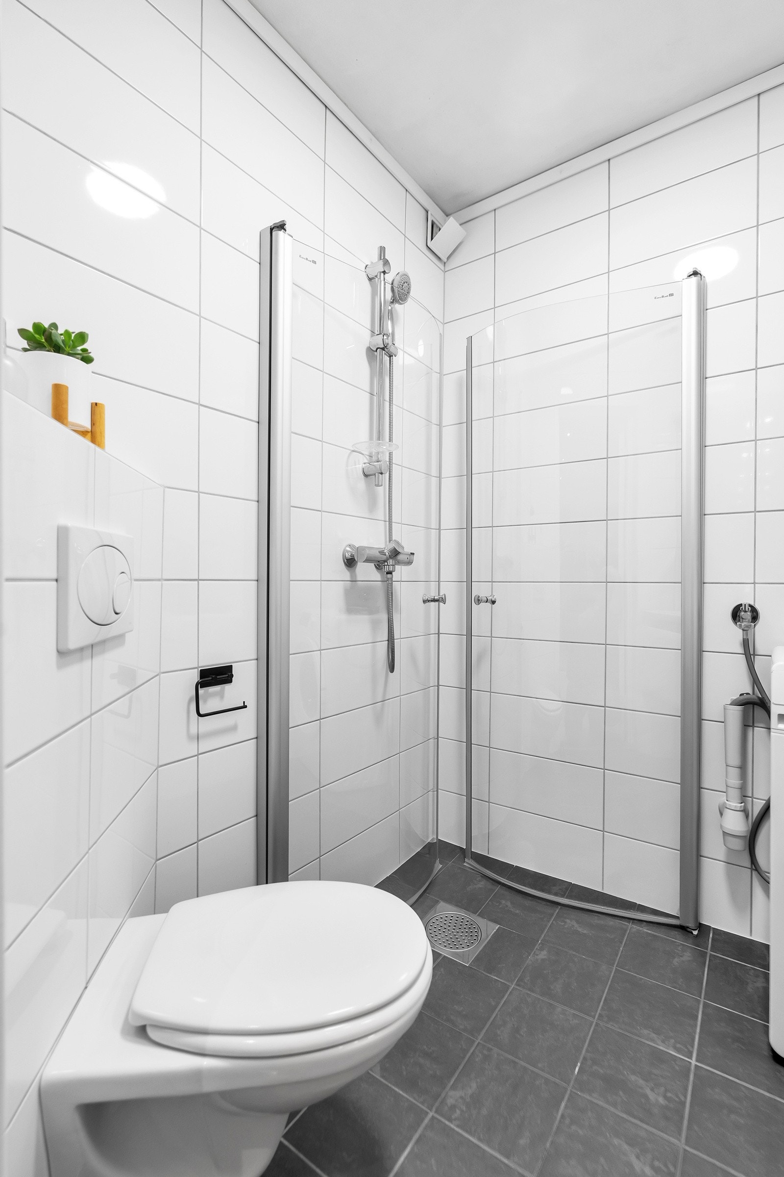 På badet er det vegghengt toalett og dusjhjørne Galleribilde