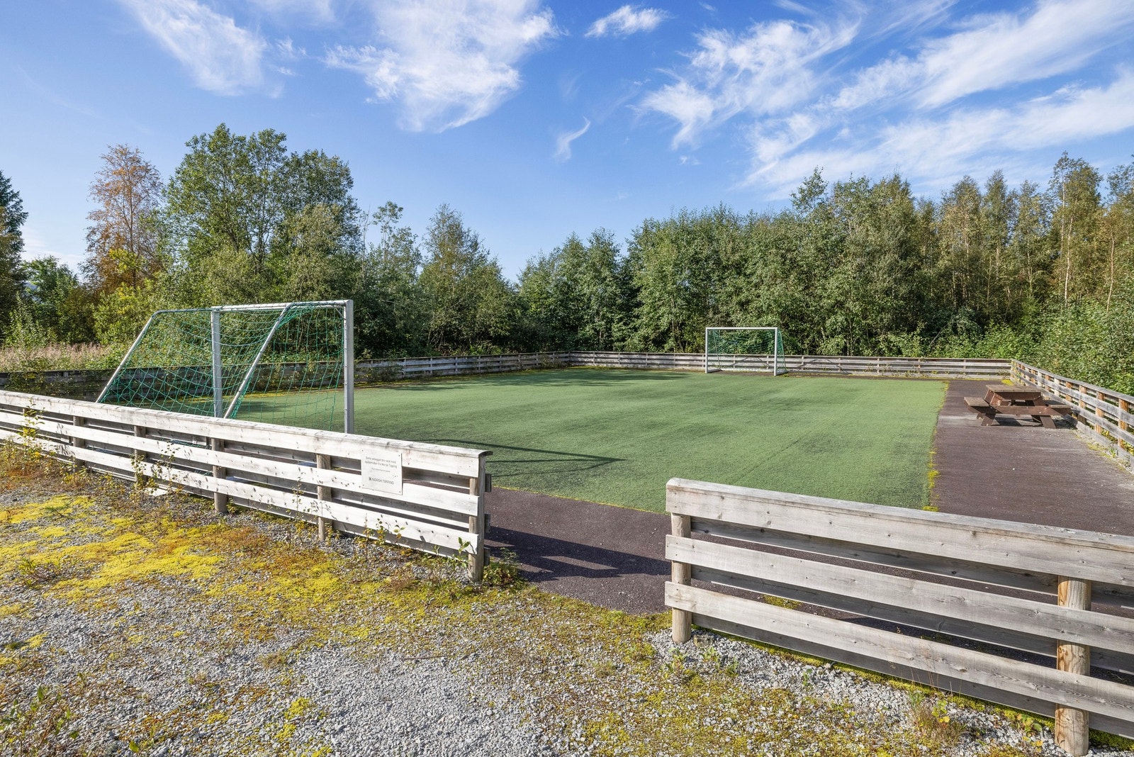 Uteareal med enkel fotballbinge og fotballbane mot vest Galleribilde