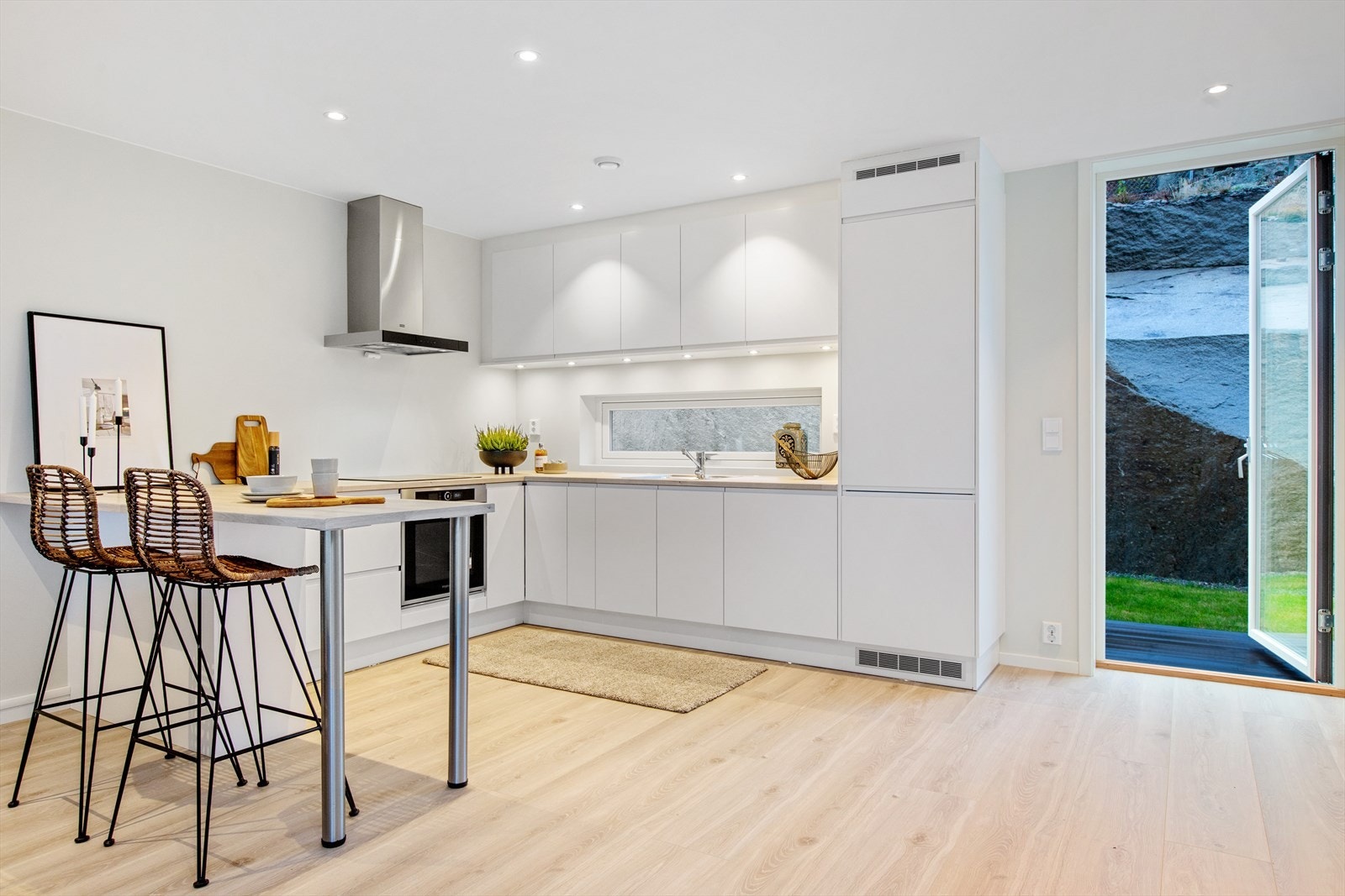 Fra kjøkken er det utgang til uteplass bak boligen med platting og gressareale. Galleribilde